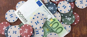 Fichas de póker online de distinto valor sobre un billete de 100 euros.
